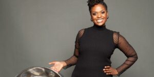 A woman wearing a black dress holding a percussion instrument