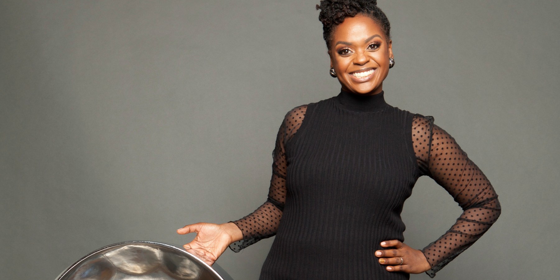 A woman wearing a black dress holding a percussion instrument