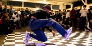 A man breakdancing in front of a crowd