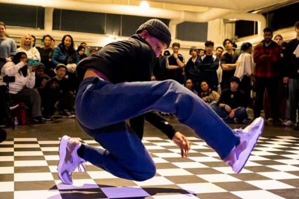 A man breakdancing in front of a crowd