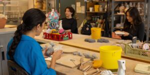 A group of artists sitting and working on ceramic pieces in the studio