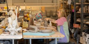 An artist sitting and working on a ceramic piece in studio