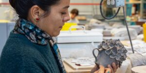 A close-up of an artist working on a ceramic cup piece in studio