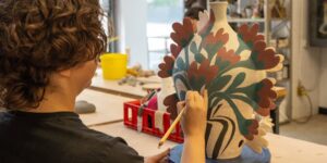 An artist sketching on a ceramic piece in studio