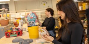 A close-up of an artist working on a ceramic piece in studio