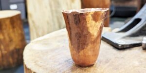 A copper cup sitting on a wood table