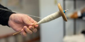 A close-up shot of a hand spinning thread