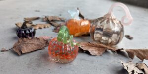 Glass pumpkin ornament next to dried leaves