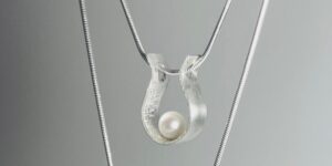 Close-up of a silver pendant necklace with a pearl