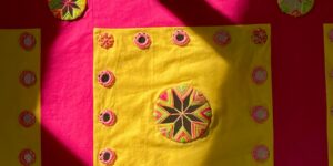 A bright yellow fabric embroidery against a bright pink background