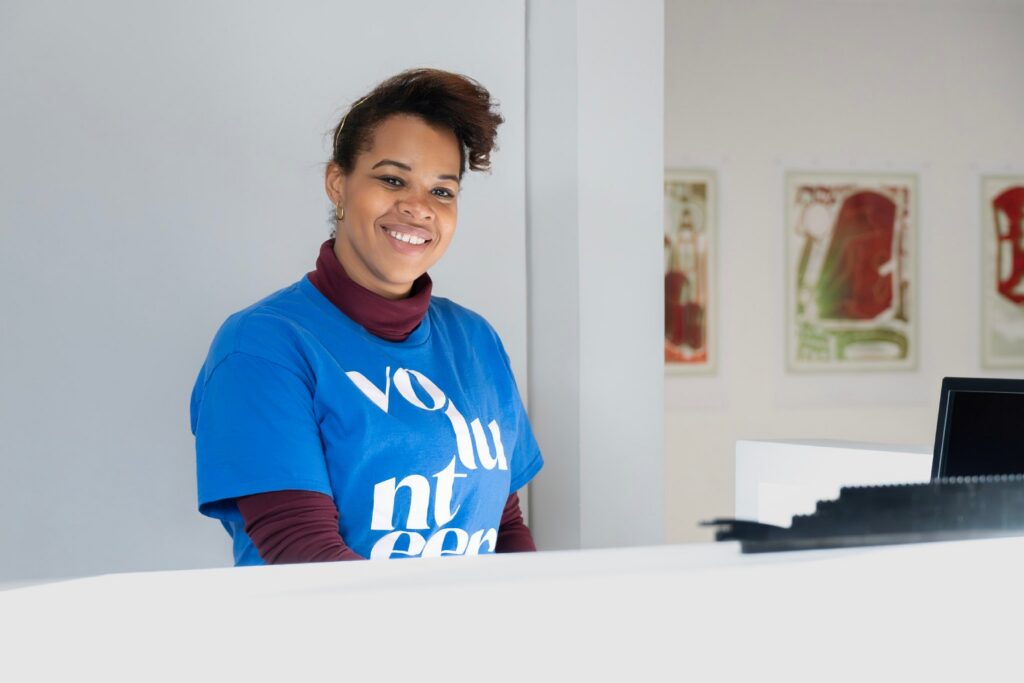 A volunteer wearing a blue shirt posing at an art gallery
