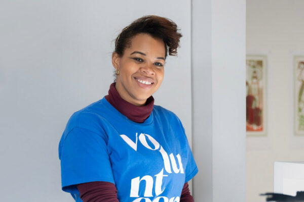 A volunteer wearing a blue shirt posing at an art gallery