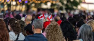 A crowd of people sitting in seats holding small Canadian flags