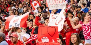 A crowd of fans cheering for a Canadian team holding signs