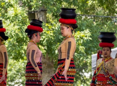 A group of women in red attire doing a performance on stage.