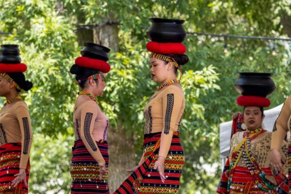 A group of women in red attire doing a performance on stage.