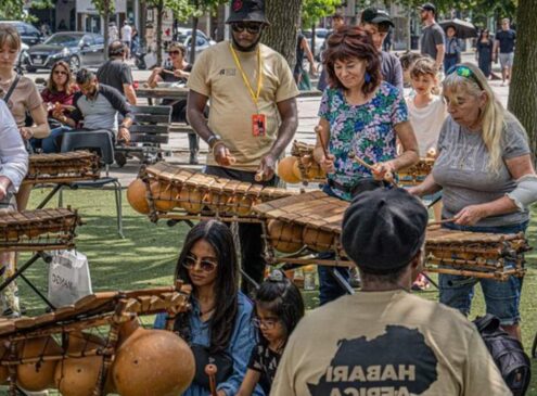 A group of people playing a percussion instrument outside at a festival