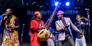 Four musicians on stage holding their musical instruments.