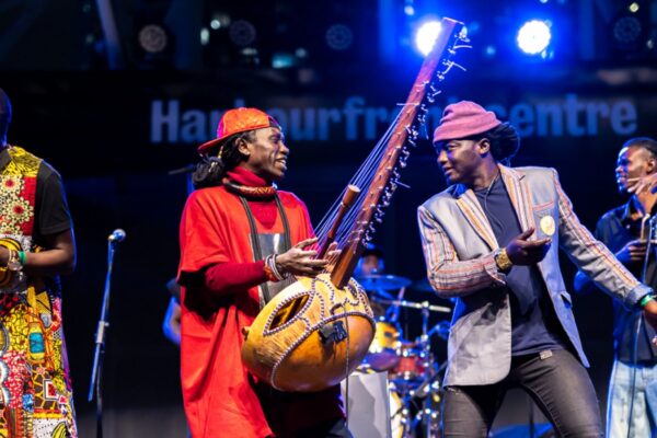 Four musicians on stage holding their musical instruments.