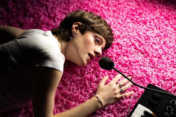 A person lying down on a pink floor holding a microphone