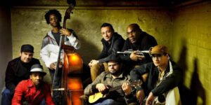 A group of musicians sitting and posing with their musical instruments.