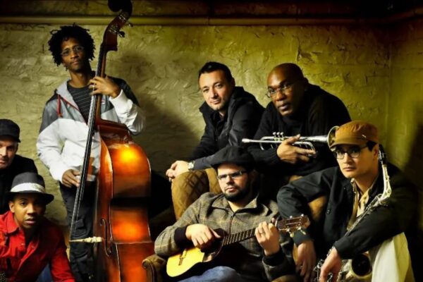 A group of musicians sitting and posing with their musical instruments.