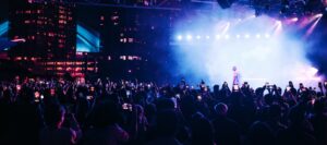 An artist performing on stage before a crowd at night.