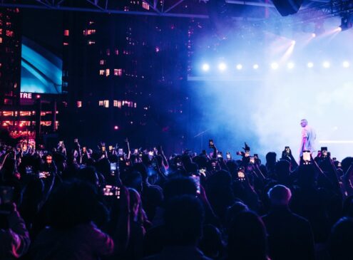 An artist performing on stage before a crowd at night.