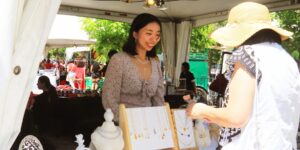 A woman selling her art under a tent to a customer outside