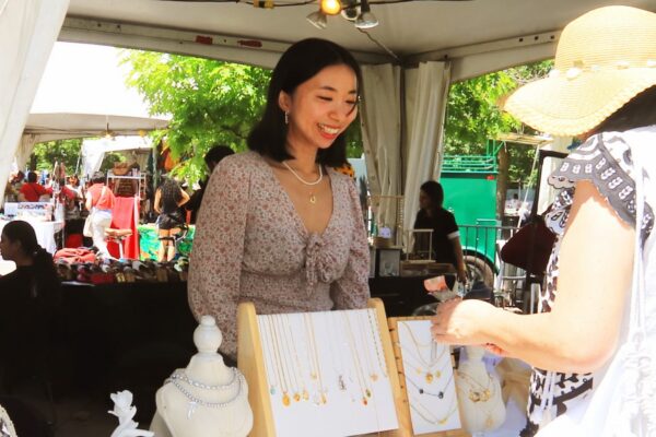 A woman selling her art under a tent to a customer outside
