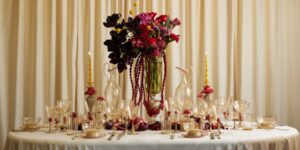A table setting with florals and glassware against a pale curtain background.