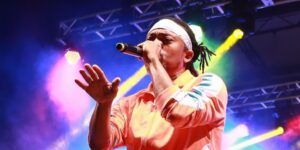 A musician singing on stage with colourful lights