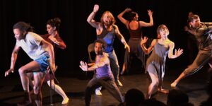 A group of dancers dancing on a dark stage