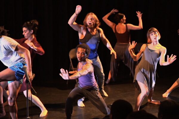 A group of dancers dancing on a dark stage