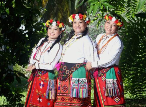 A group of three women in red attire posing for the camera