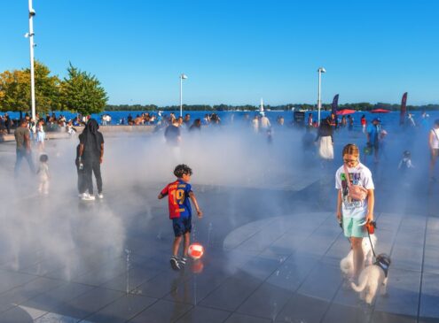 A young boy kicking a soccer ball outside by the lake