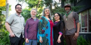 A group of five musicians posing outdoors