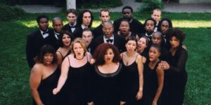 An ensemble of singers dressed in black posing outdoors