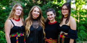 A group of four artists dressed in red and black attire outside.