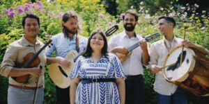 A group of five musicians posing with their instruments outdoors
