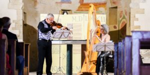 Two musicians performing in front of an audience indoors.