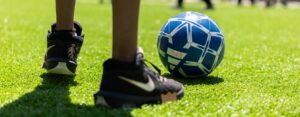 A close-up of a person kicking a soccer ball on grass