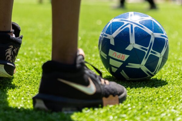 A close-up of a person kicking a soccer ball on grass