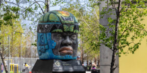 An art installation of a stone head sitting outdoors