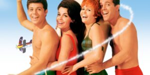 Four people in swimsuits posing next to each other smiling for the camera