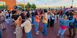A group of people dancing outdoors by the lake