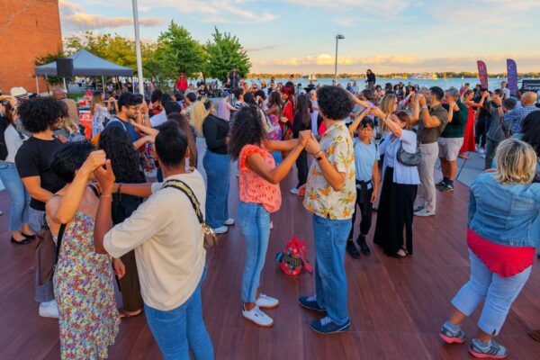 A group of people dancing outdoors by the lake