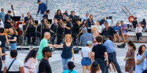 A group of people dancing outdoors by the lake