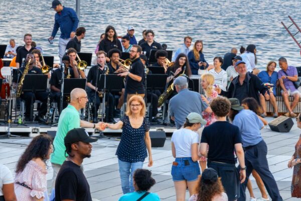 A group of people dancing outdoors by the lake