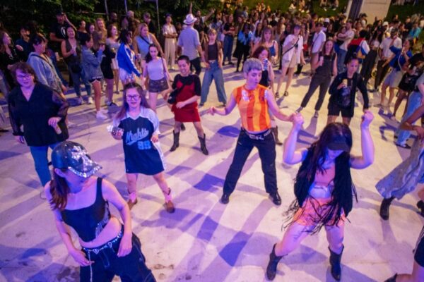A crowd of people participating in an outdoor evening dance class